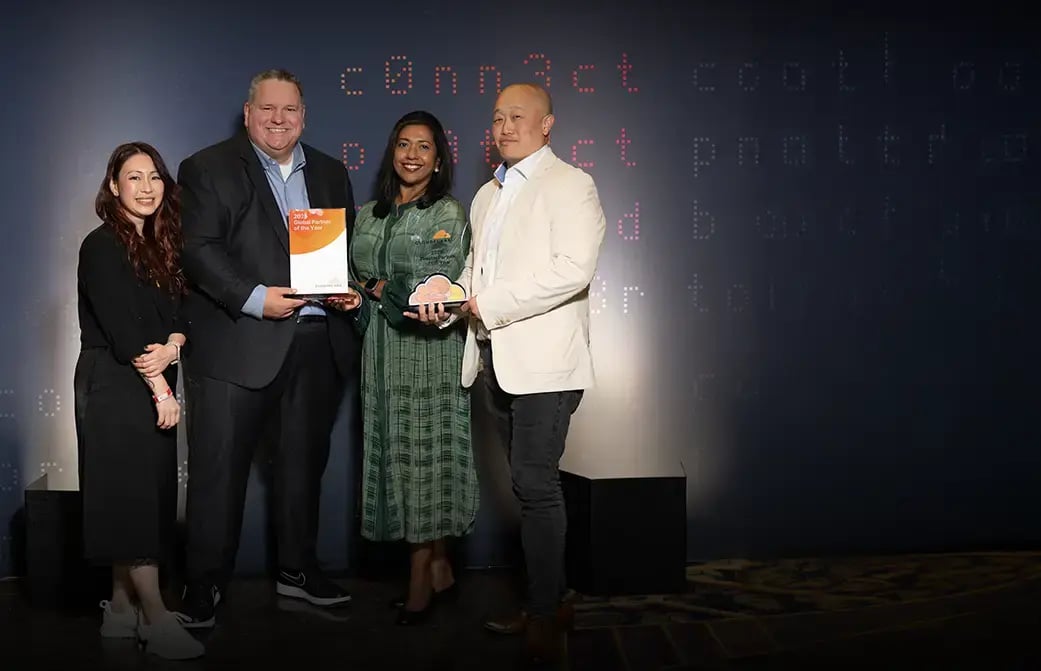 Group of people standing together holding an award in front of a dark backdrop with text.