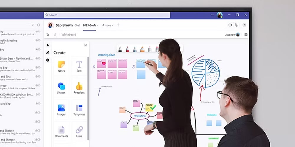 Team collaborating at a table using a large interactive whiteboard with notes and diagrams.