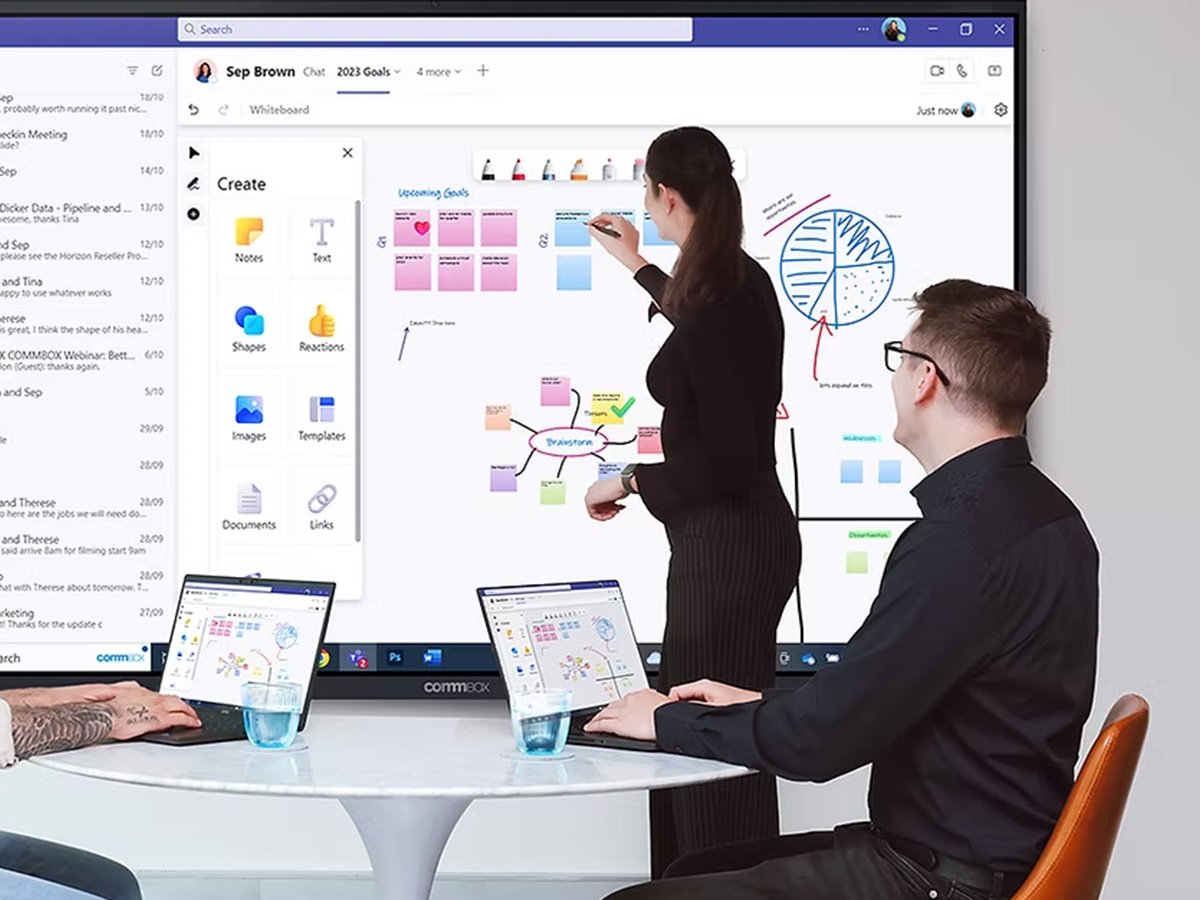 Team collaborating at a table using a large interactive whiteboard with notes and diagrams.