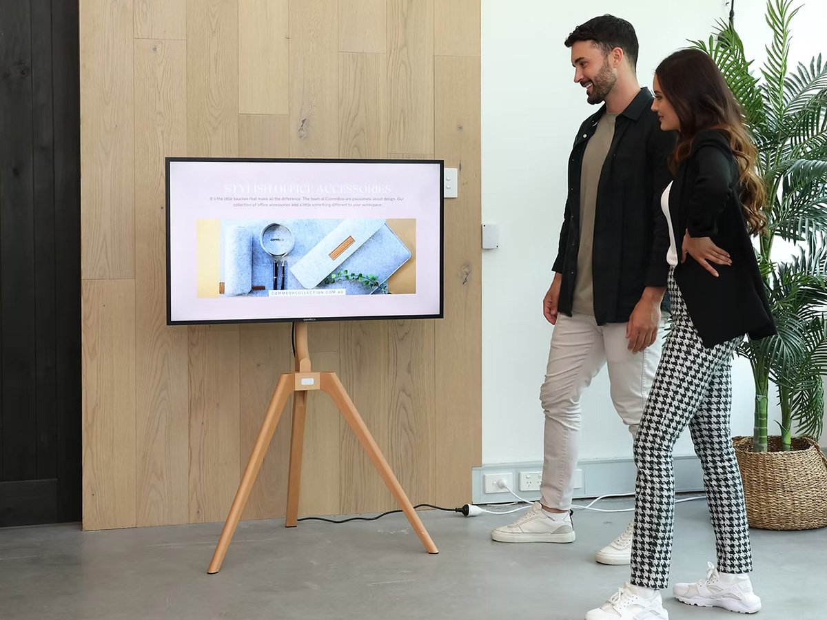 Two people viewing a digital display on a stand in a modern office environment.