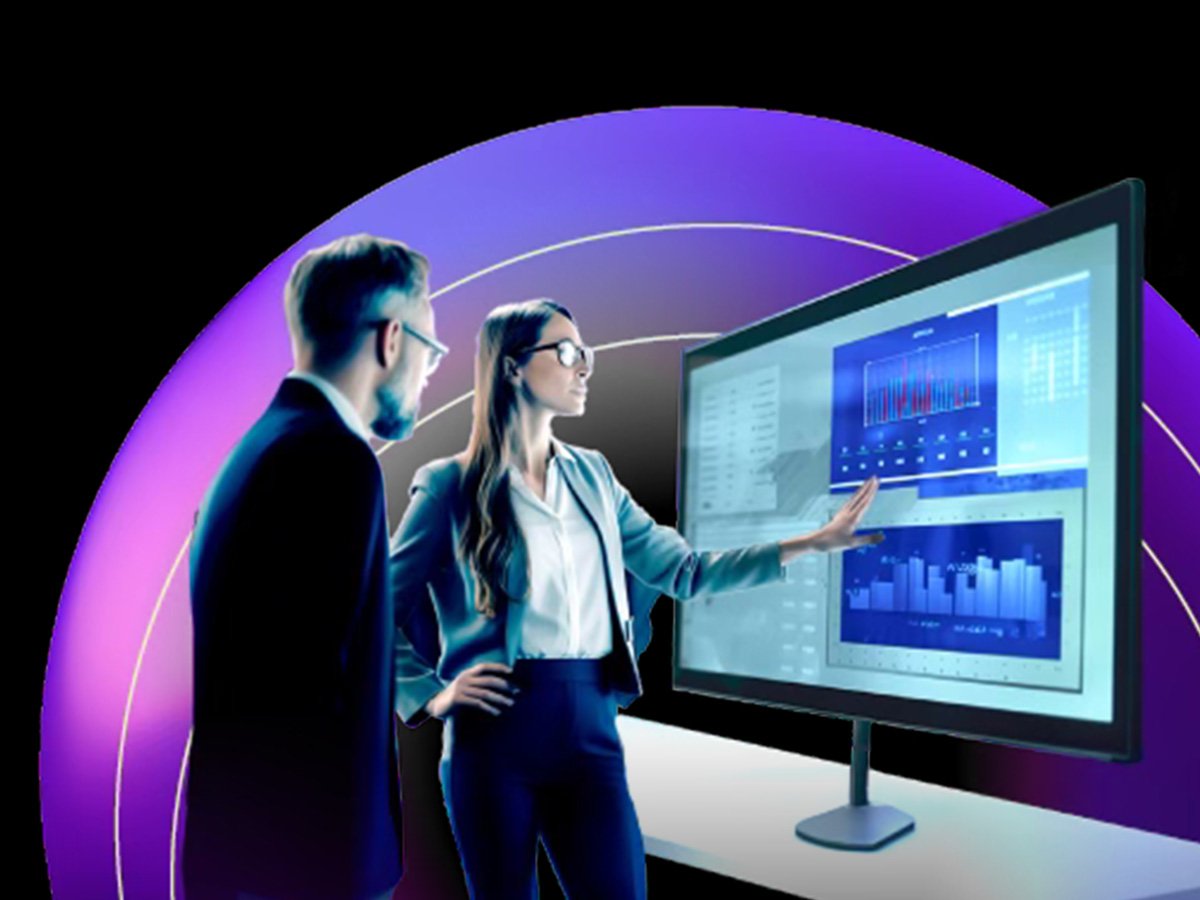 Two professionals reviewing analytics and charts on a large interactive display in a modern workspace.