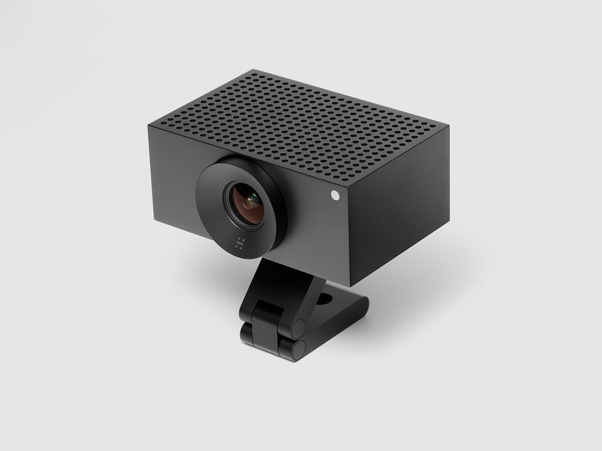 Compact black video conferencing camera on an adjustable stand.