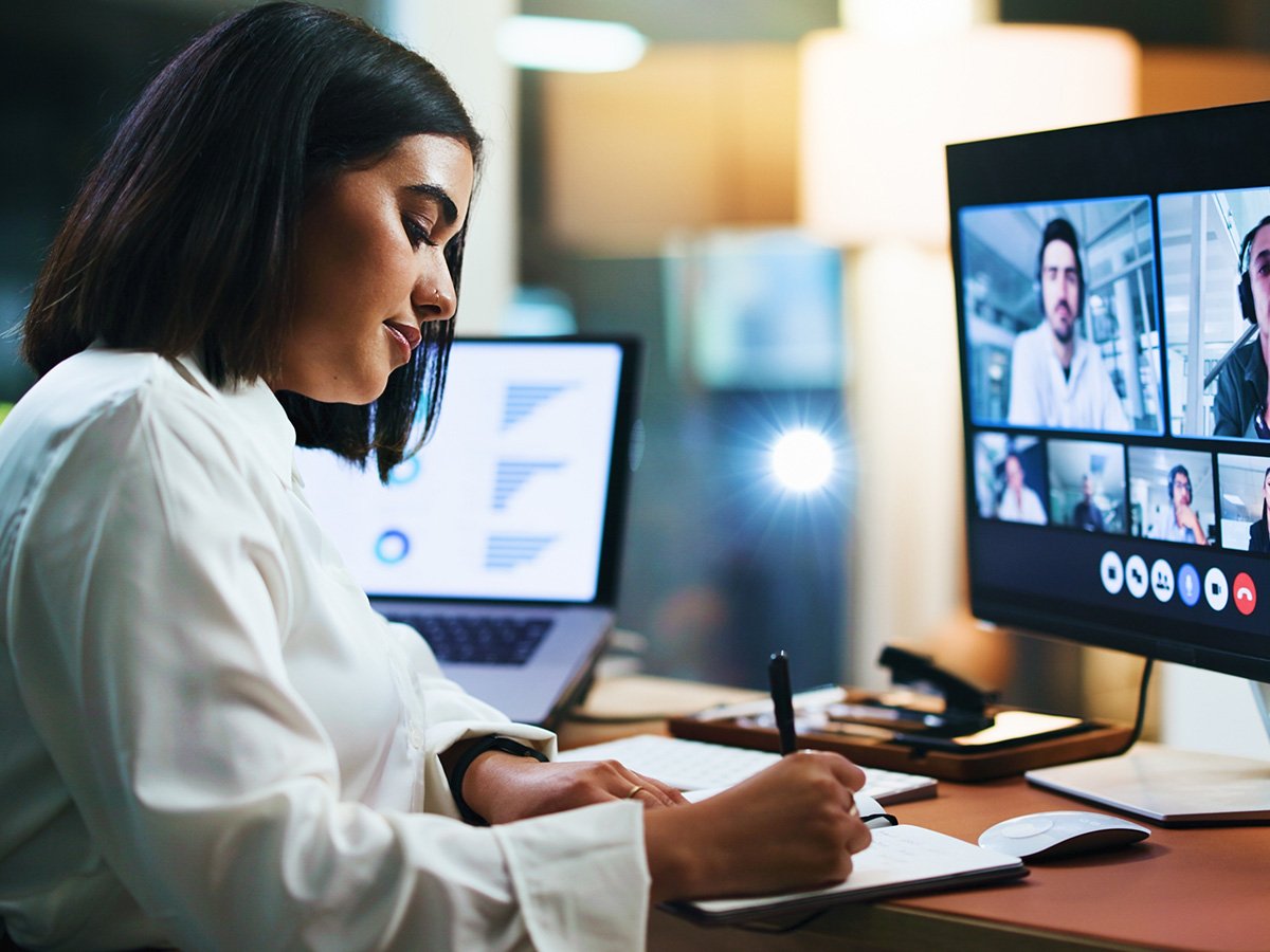 Person sitting at computer on a video call, taking notes