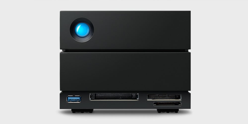 Compact black desktop device with a circular blue indicator and multiple ports on the front.