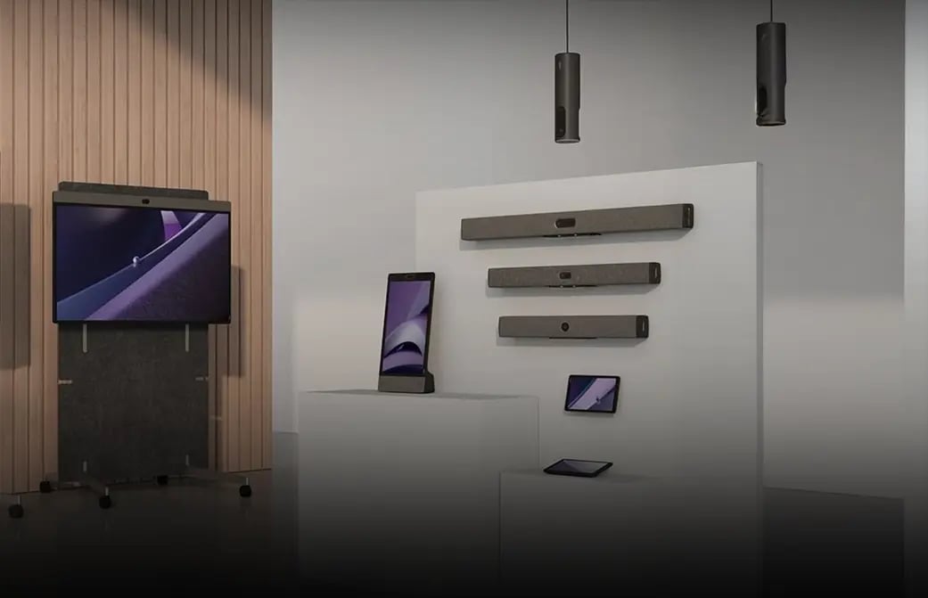 Display of modern video conferencing devices and screens arranged in a showroom setting.