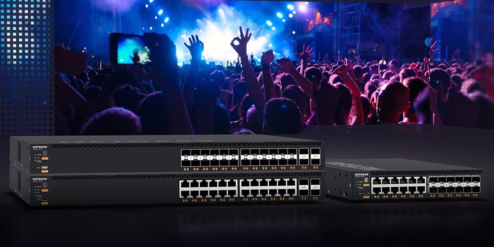 Netgear switches displayed in front of a large concert crowd with colorful lighting.