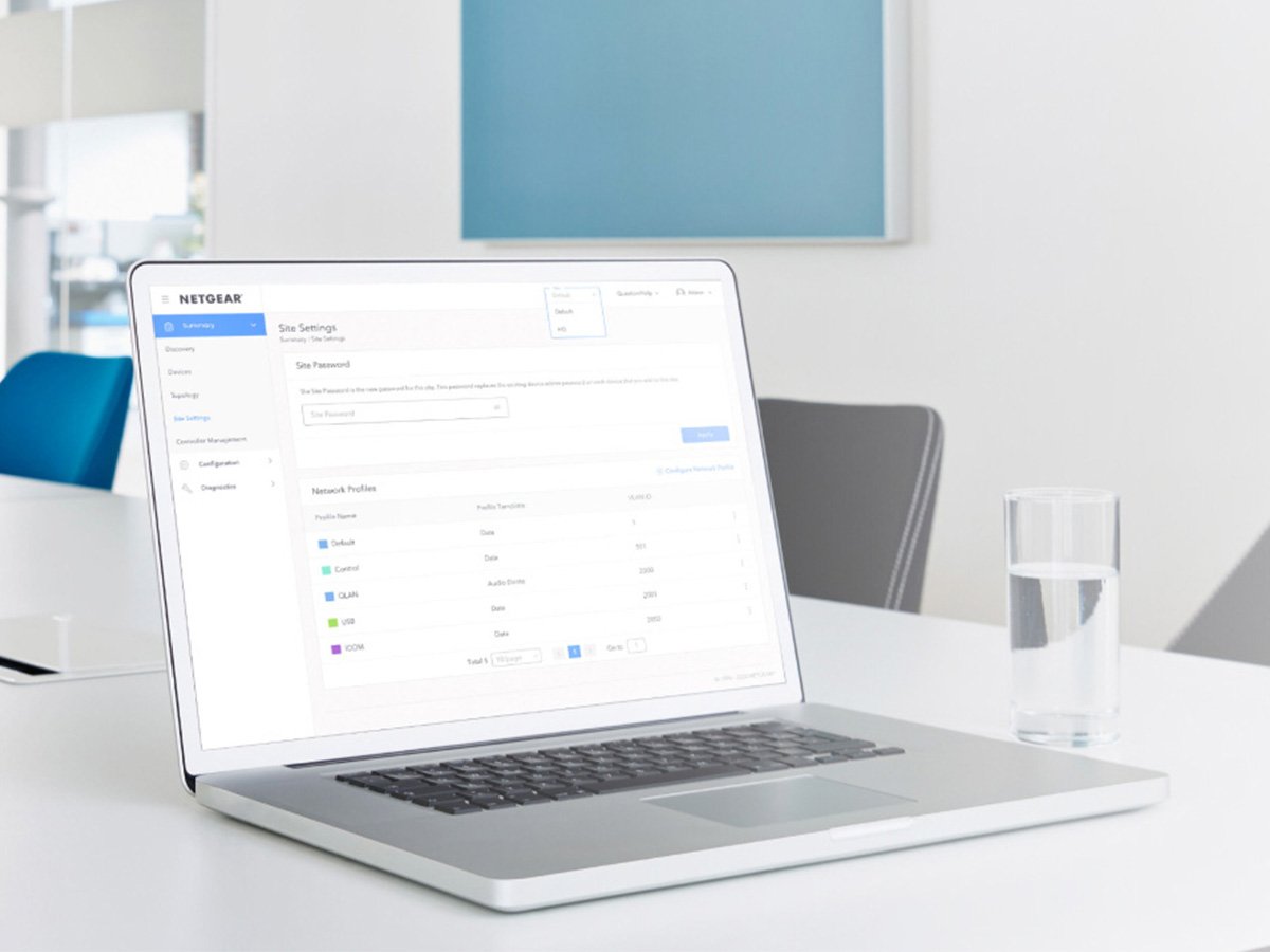 Laptop showing Netgear network management settings on a clean office desk.