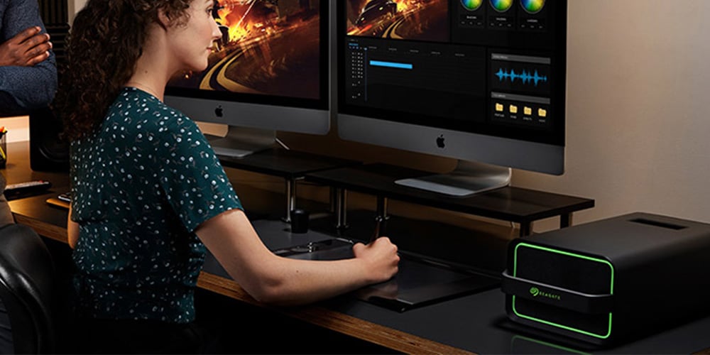 Dual‑screen desktop workstation displaying video editing software with color wheels, timelines, and preview monitors.