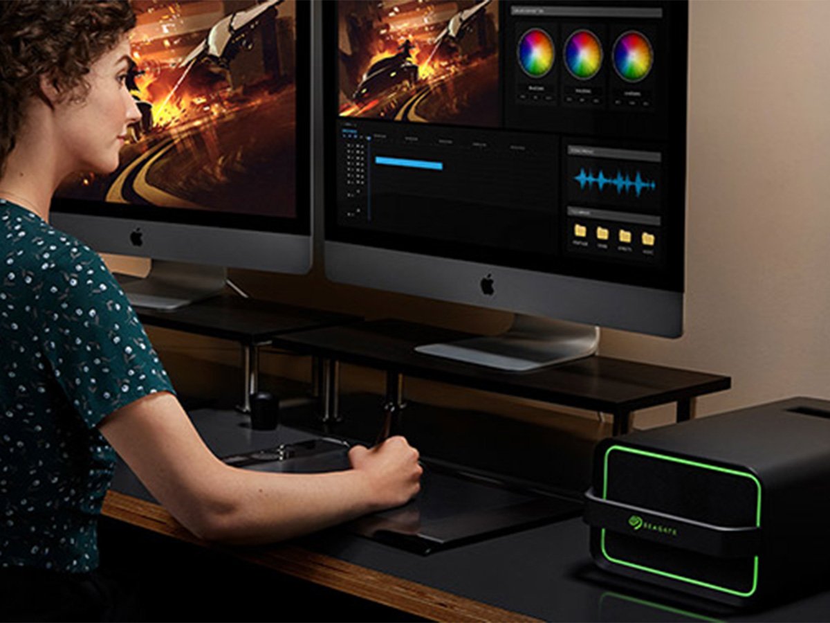 Dual‑screen desktop workstation displaying video editing software with color wheels, timelines, and preview monitors.