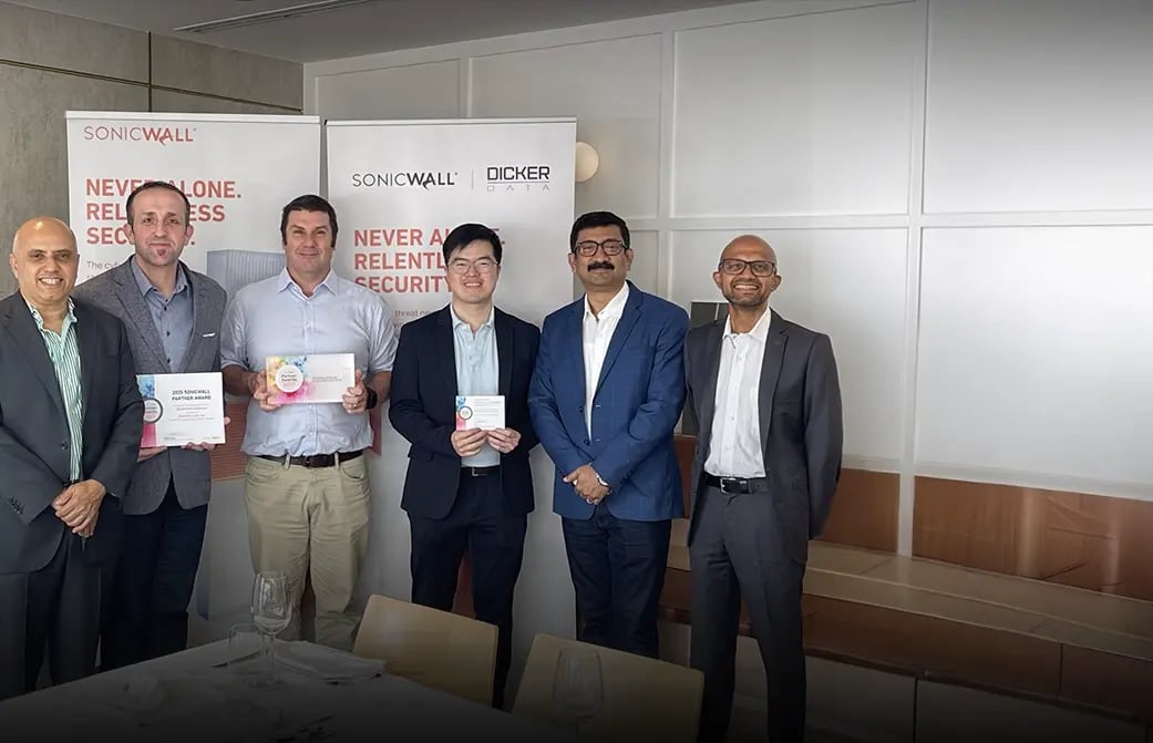 Group of business professionals holding awards, standing in front of SonicWall and Dicker Data branded banners.