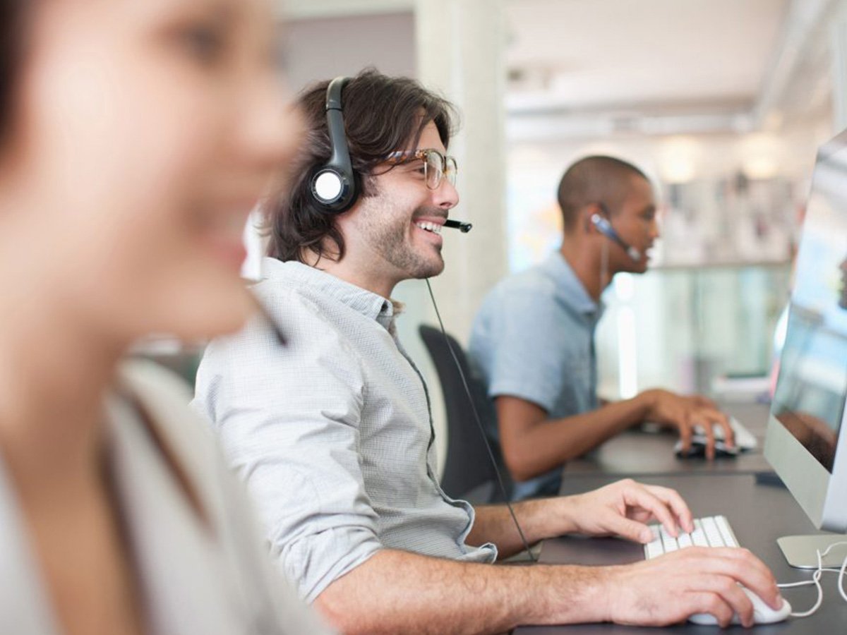 People working at desktop computers in an open-plan office environment.