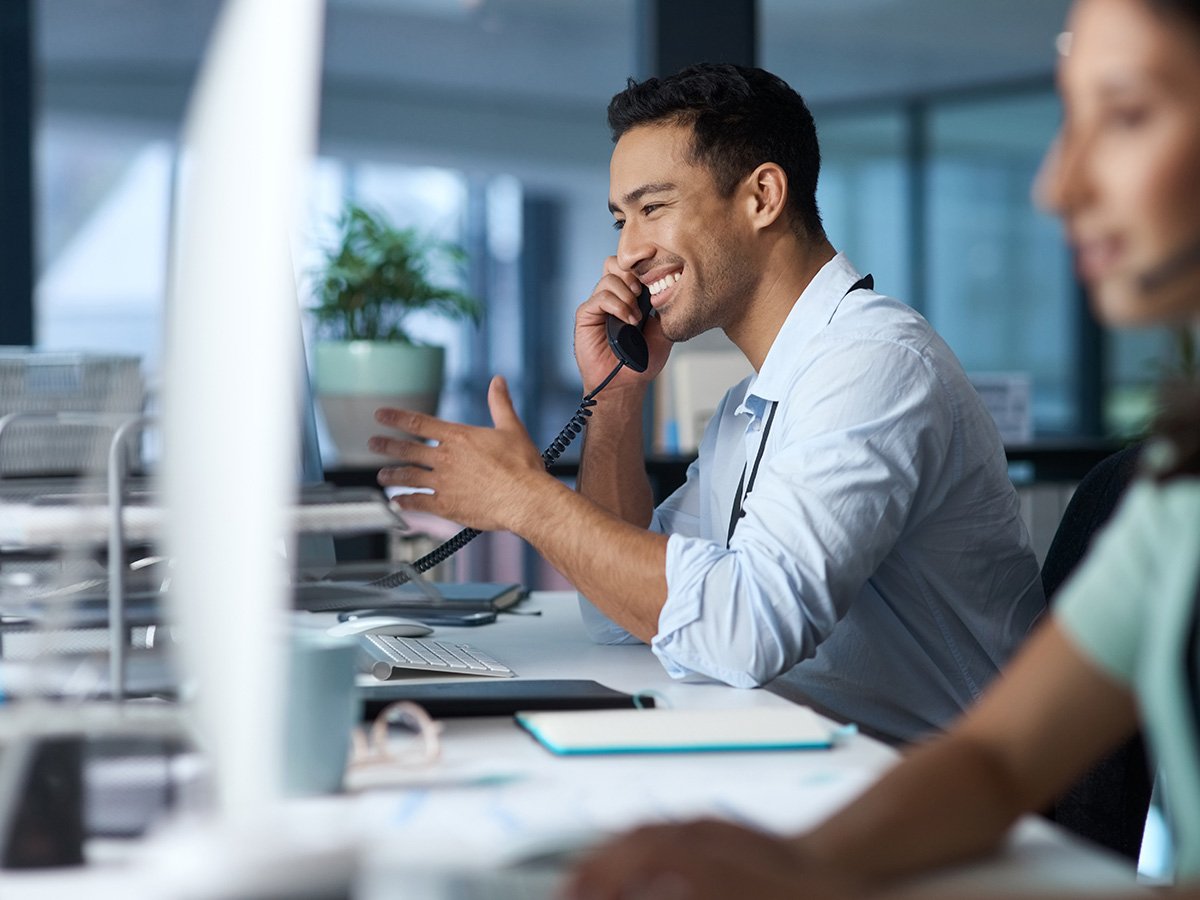 Person talking on the phone while sitting at an office desk infront of computer