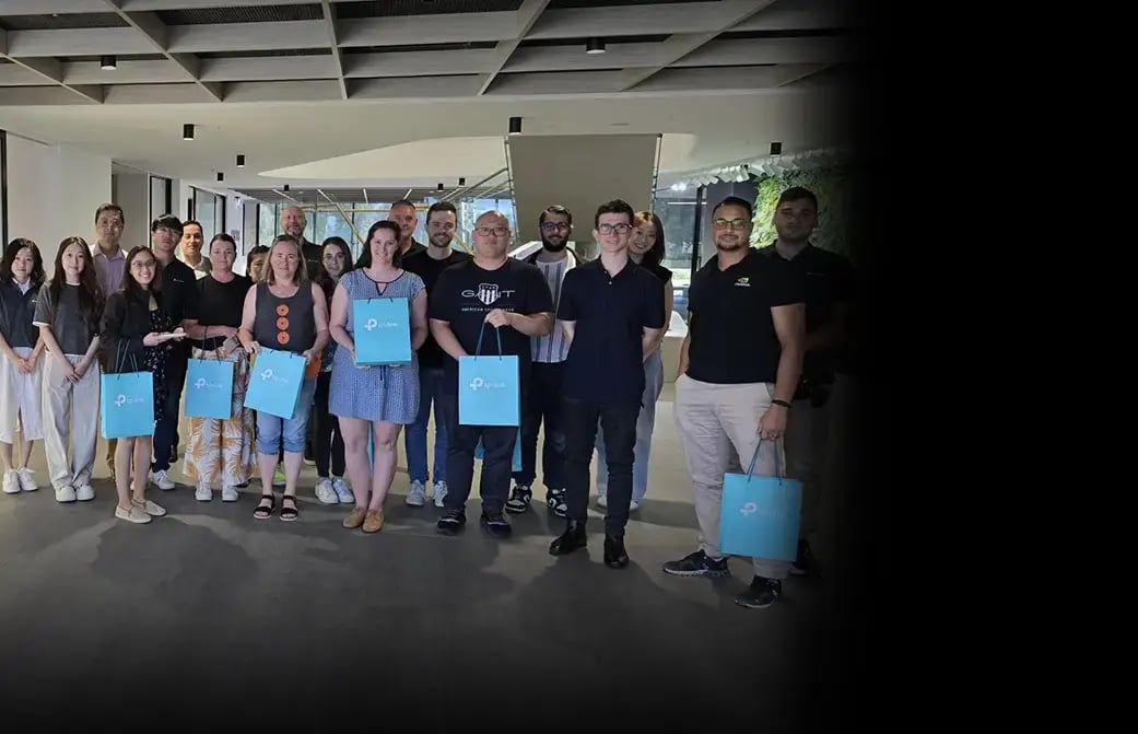 Group of people standing indoors holding branded gift bags during a workplace or company event.
