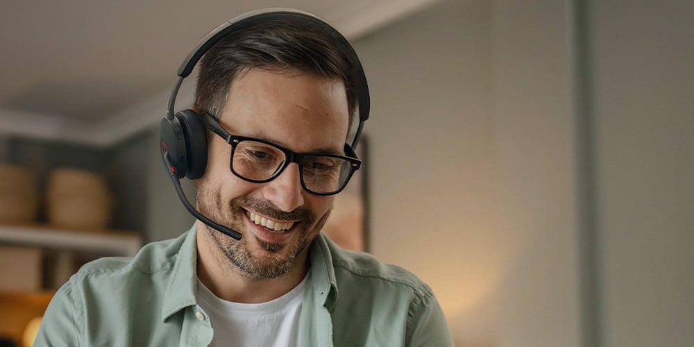Remote worker wearing a headset and using a laptop in a home office setting.