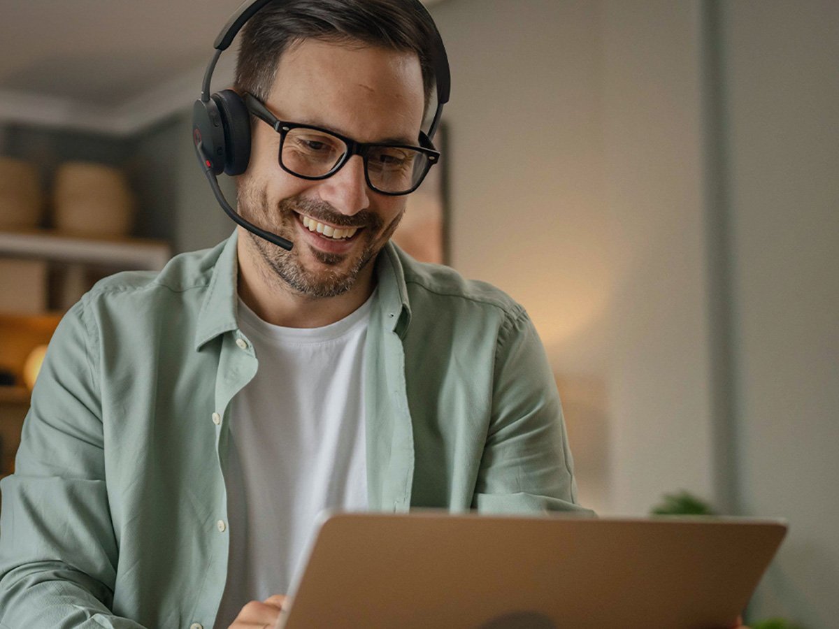 Remote worker wearing a headset and using a laptop in a home office setting.