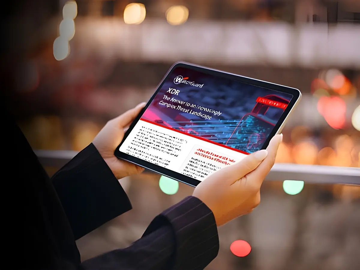 A person holding a tablet displaying a presentation on XR technology, with text and graphs visible. The background shows a blurred view of lights and colors, suggesting an urban setting.