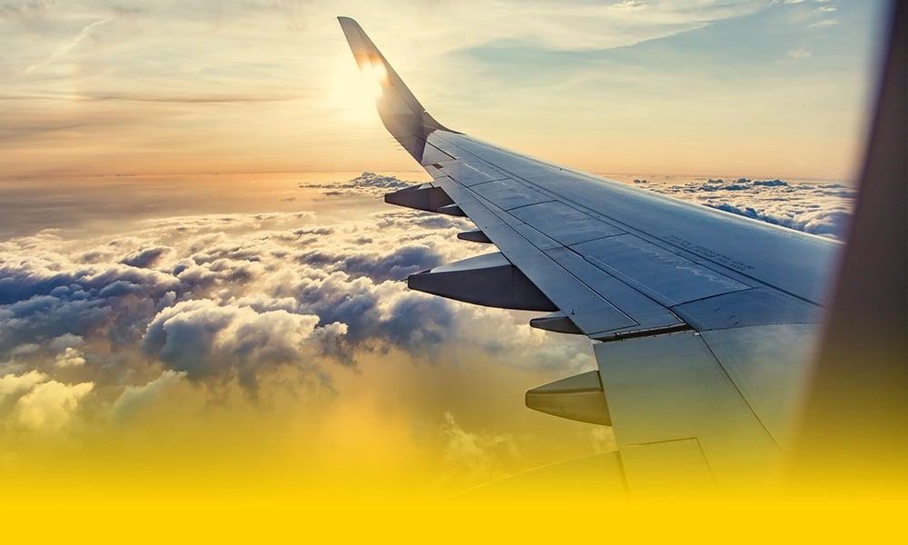 Airplane wing above clouds at sunset.