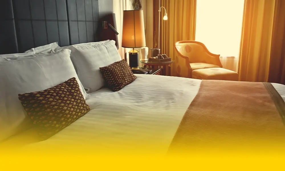 Sunlit hotel bedroom with armchair.