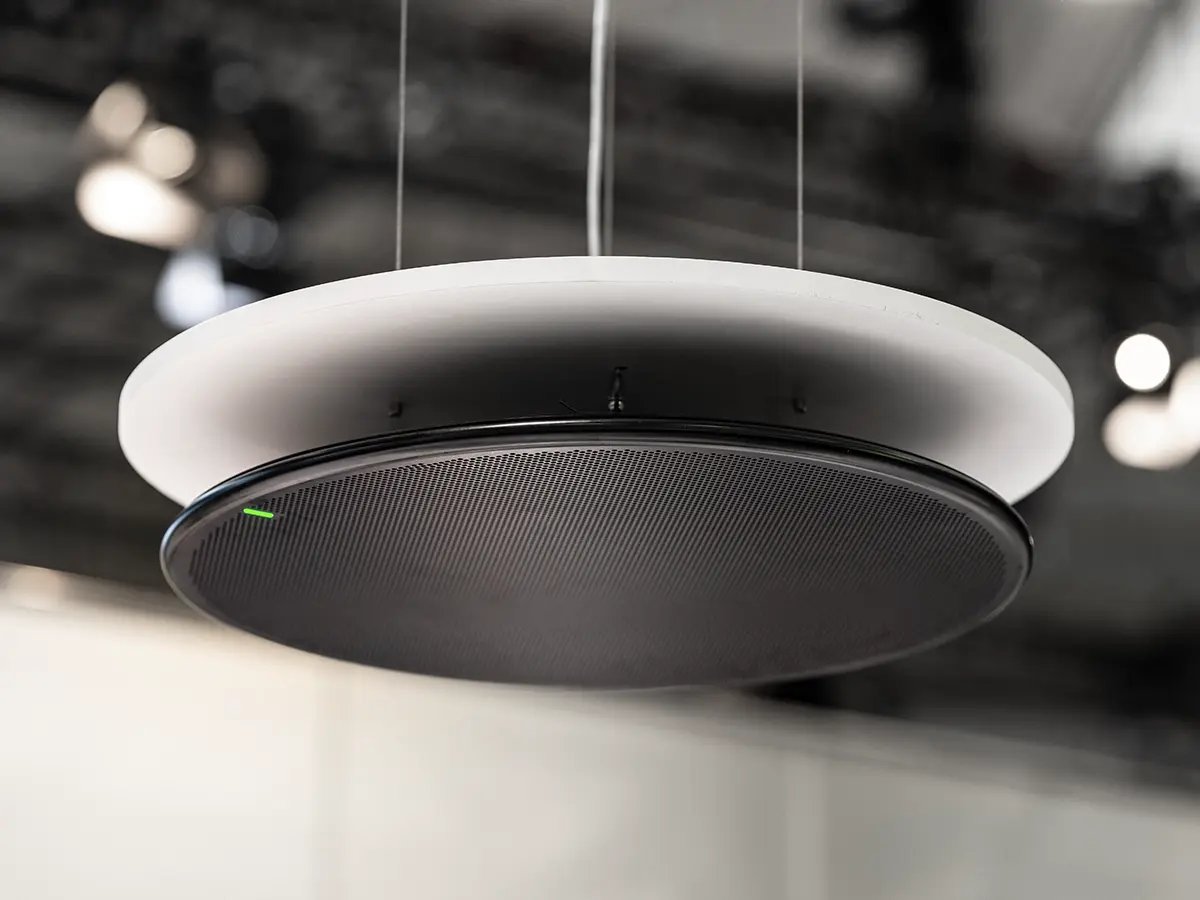 A circular Shure ceiling microphone suspended from the ceiling at an event or showroom.