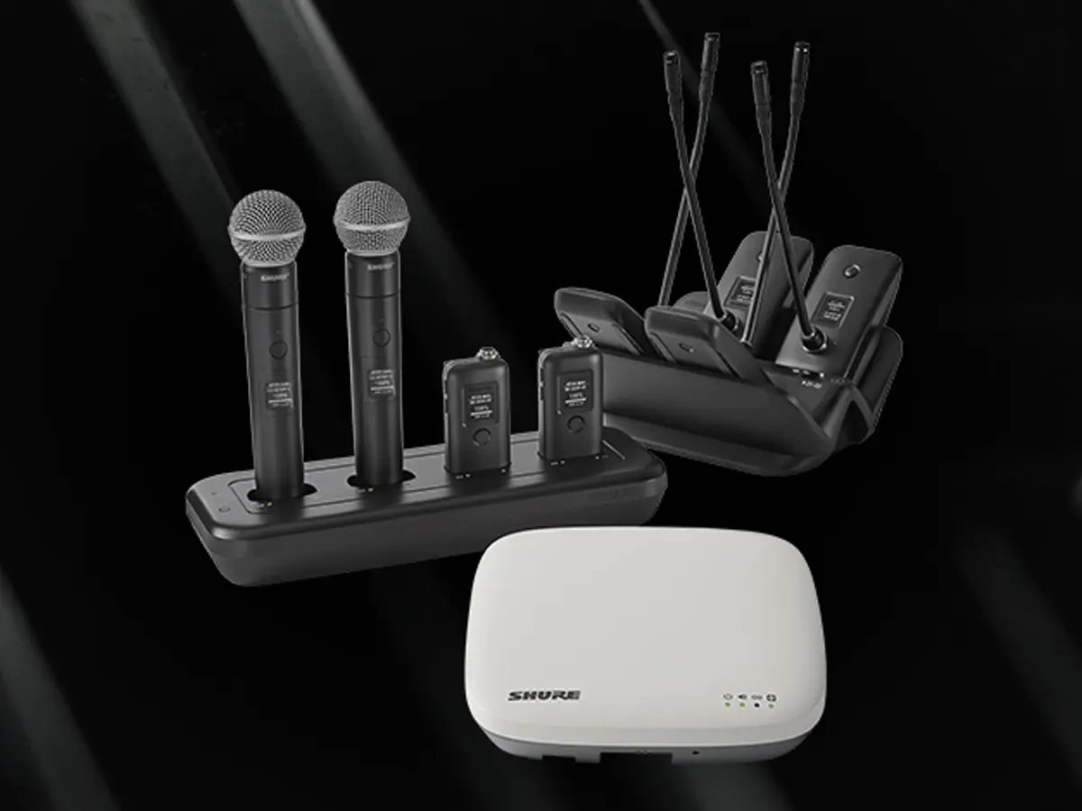 Wireless microphone system with handheld mics, bodypack transmitters, charging docks, and a compact receiver on a dark background.