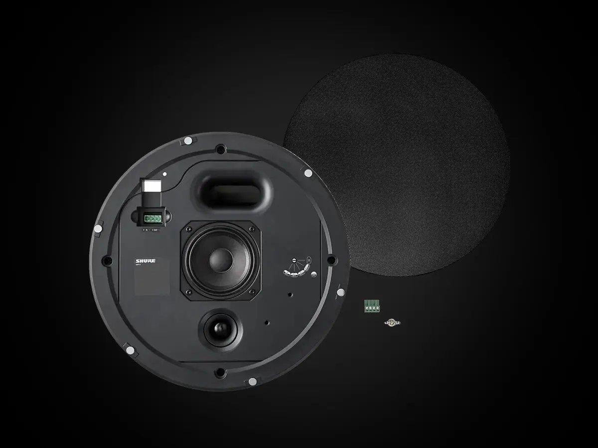 Round ceiling speaker with exposed internal components and a detached black grille.