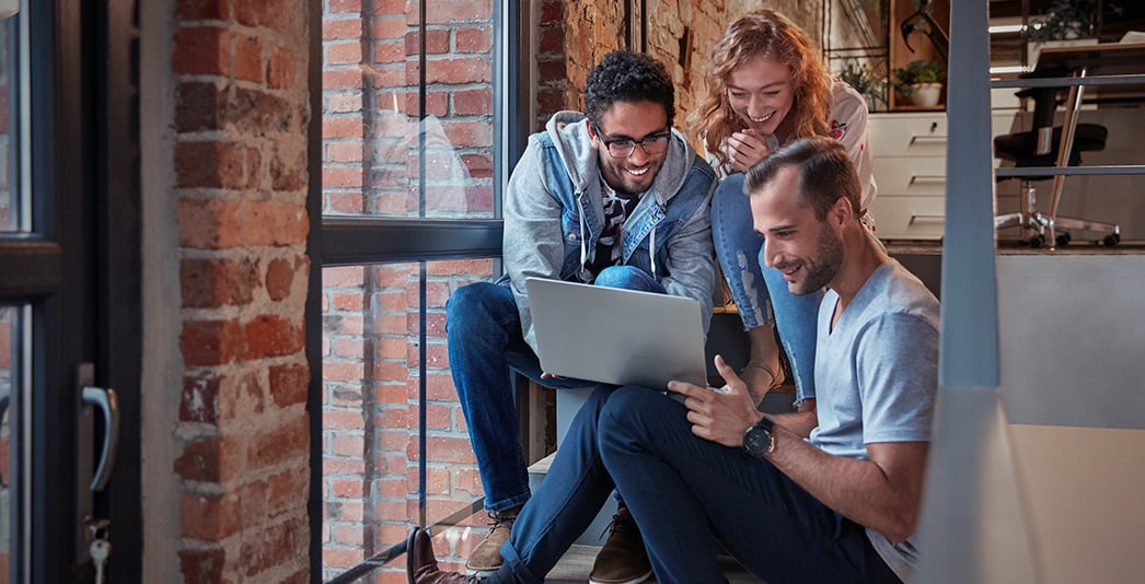 Group of workers in the office looking at a laptop screen