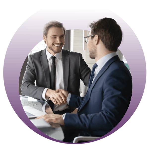 Two people in business suits shaking hands across a table.