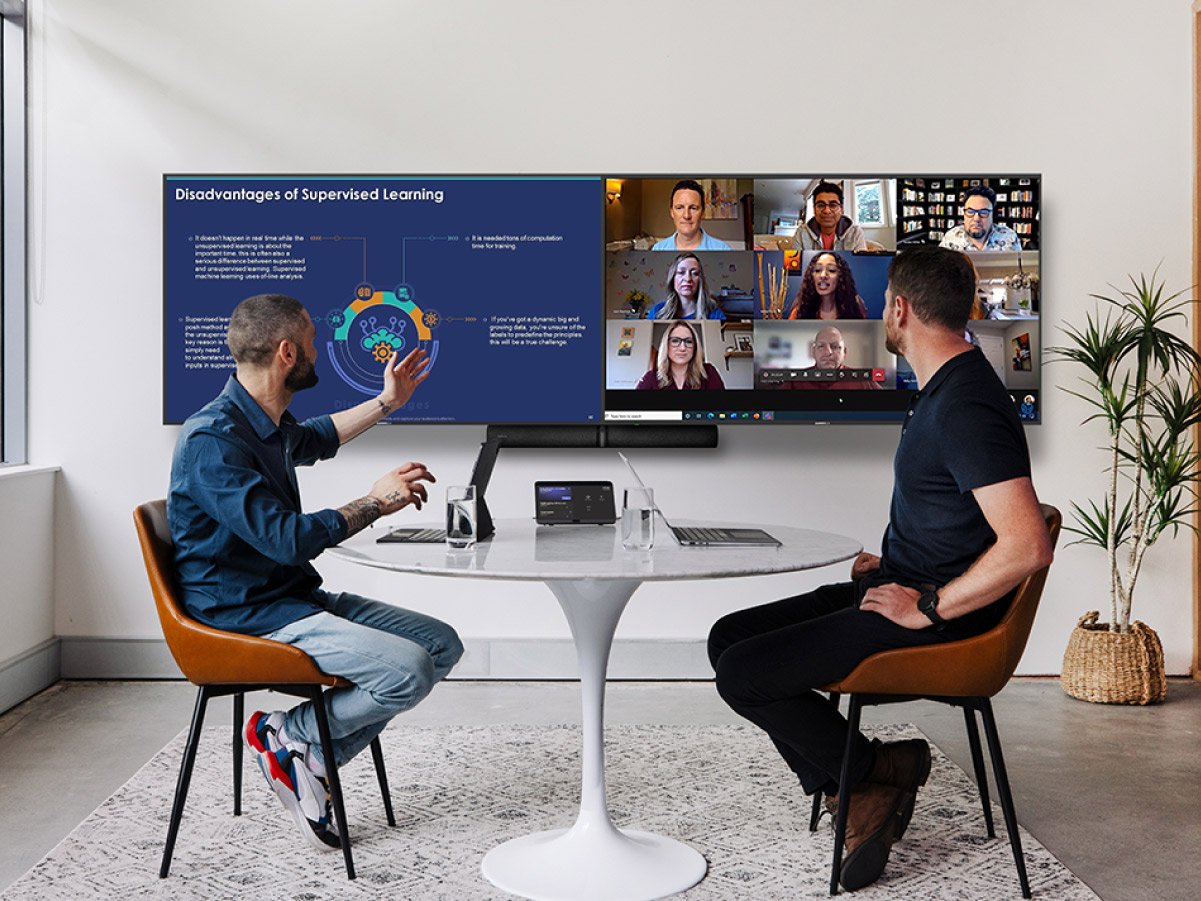 Two people in a meeting conference call facing a big double screen