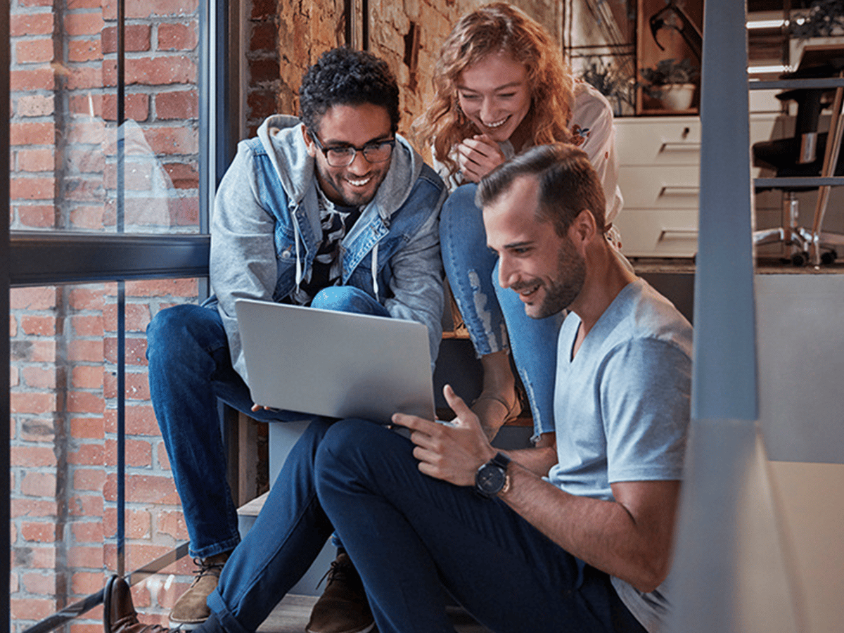 Group of workers in the office looking at a laptop screen
