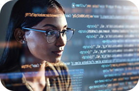 "Person with glasses looking at a computer screen displaying code.